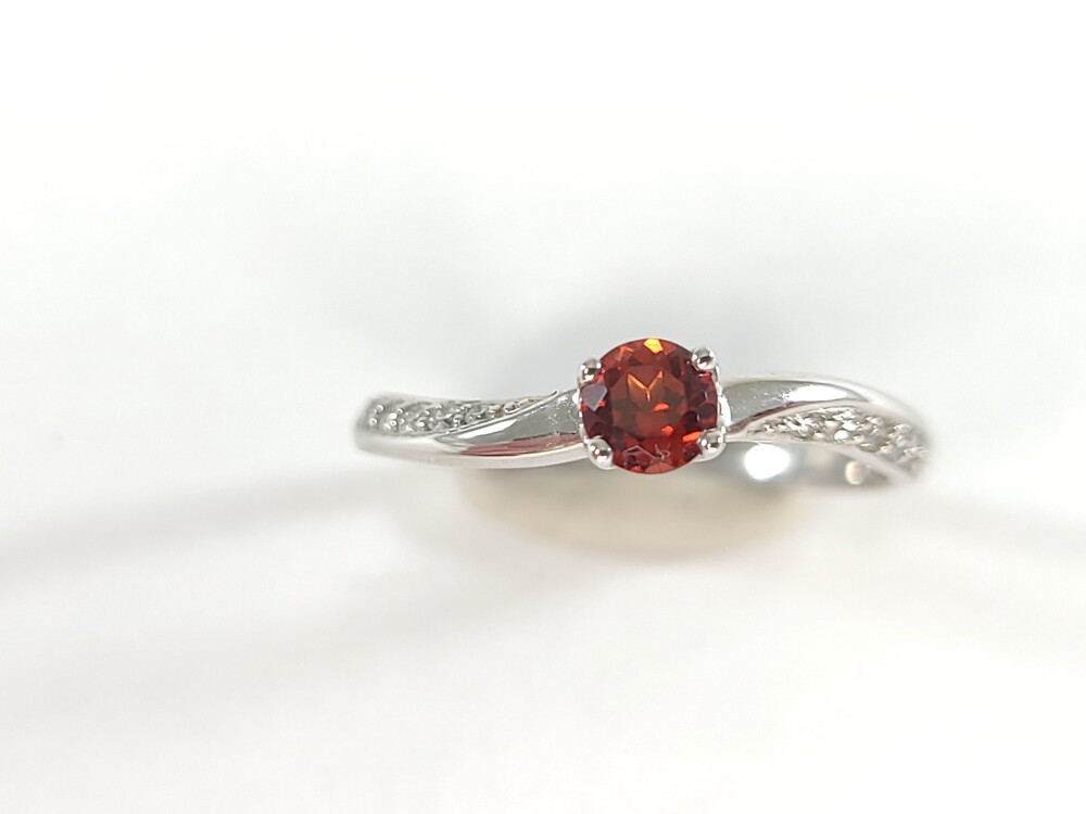 Ring crafted in white gold, featuring a garnet and a total of 9 points of diamonds.